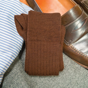 pair of Light Brown Merino Wool Mid Calf Dress Socks laying on top of nice clothing