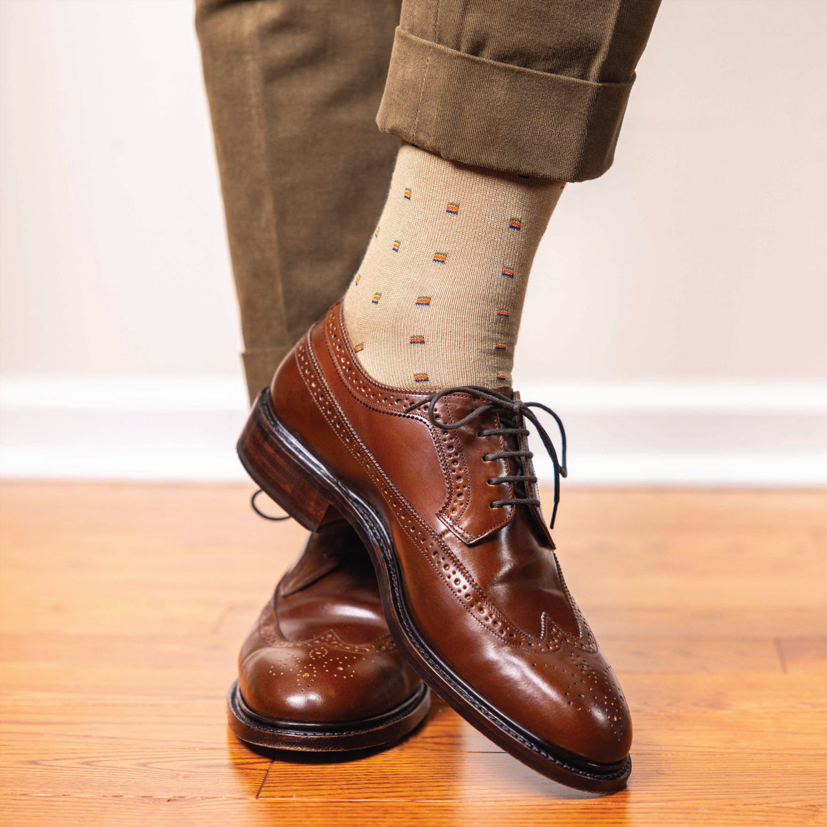 man wearing over the calf length khaki dress socks with a square knot pattern and nice dress shoes