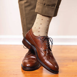 man wearing over the calf length khaki dress socks with a square knot pattern and nice dress shoes