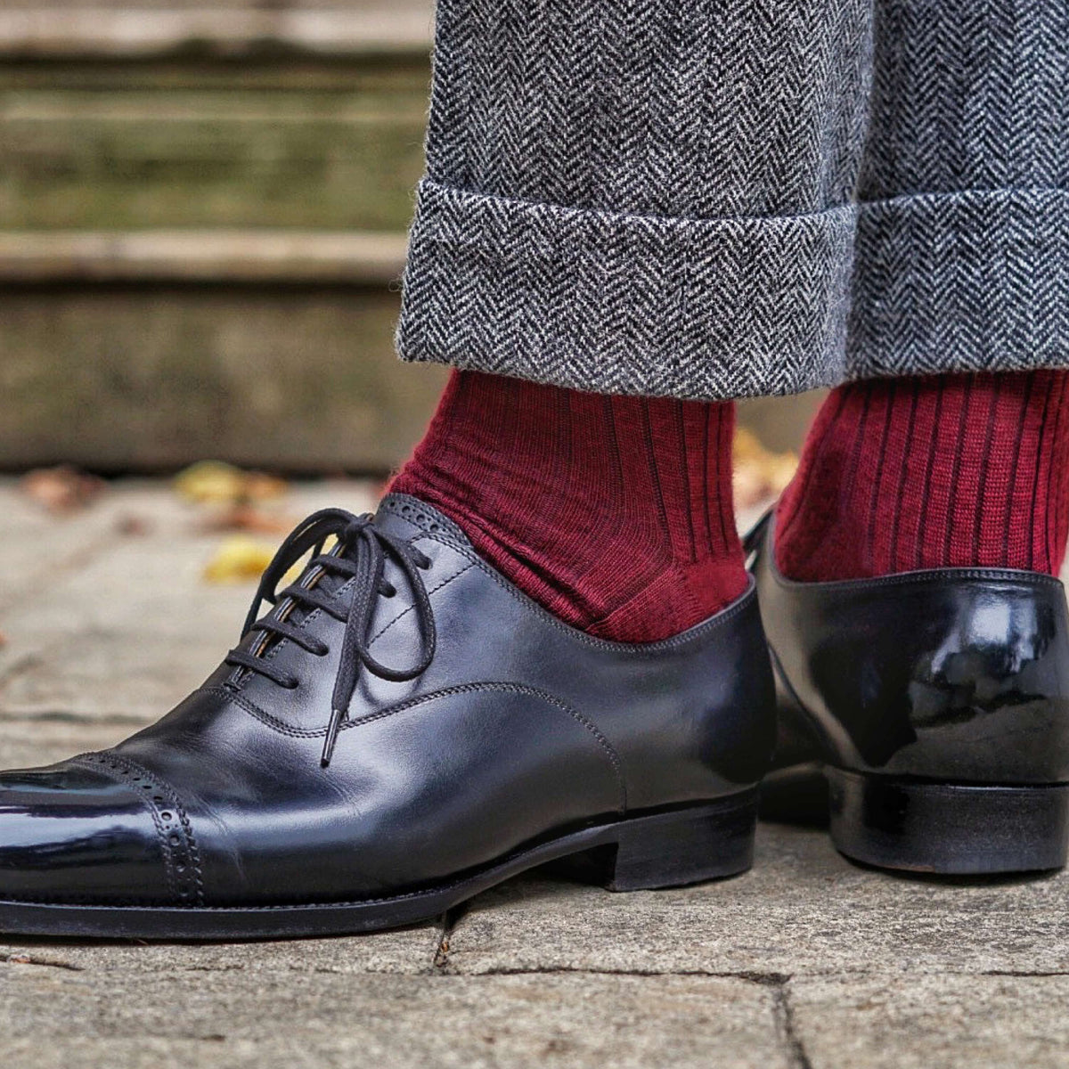 lifestyle image of  man standing outside wearing burgundy merino wool over the calf ribbed mens dress socks