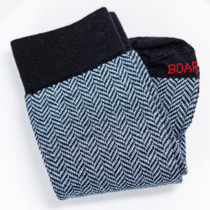 folded pair of light blue and black herringbone dress socks on top of white table