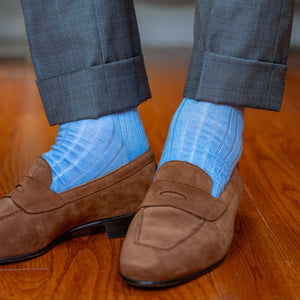 man standing on hardwood floor wearing light blue ribbed dress socks with grey suit and light brown suede penny loafers