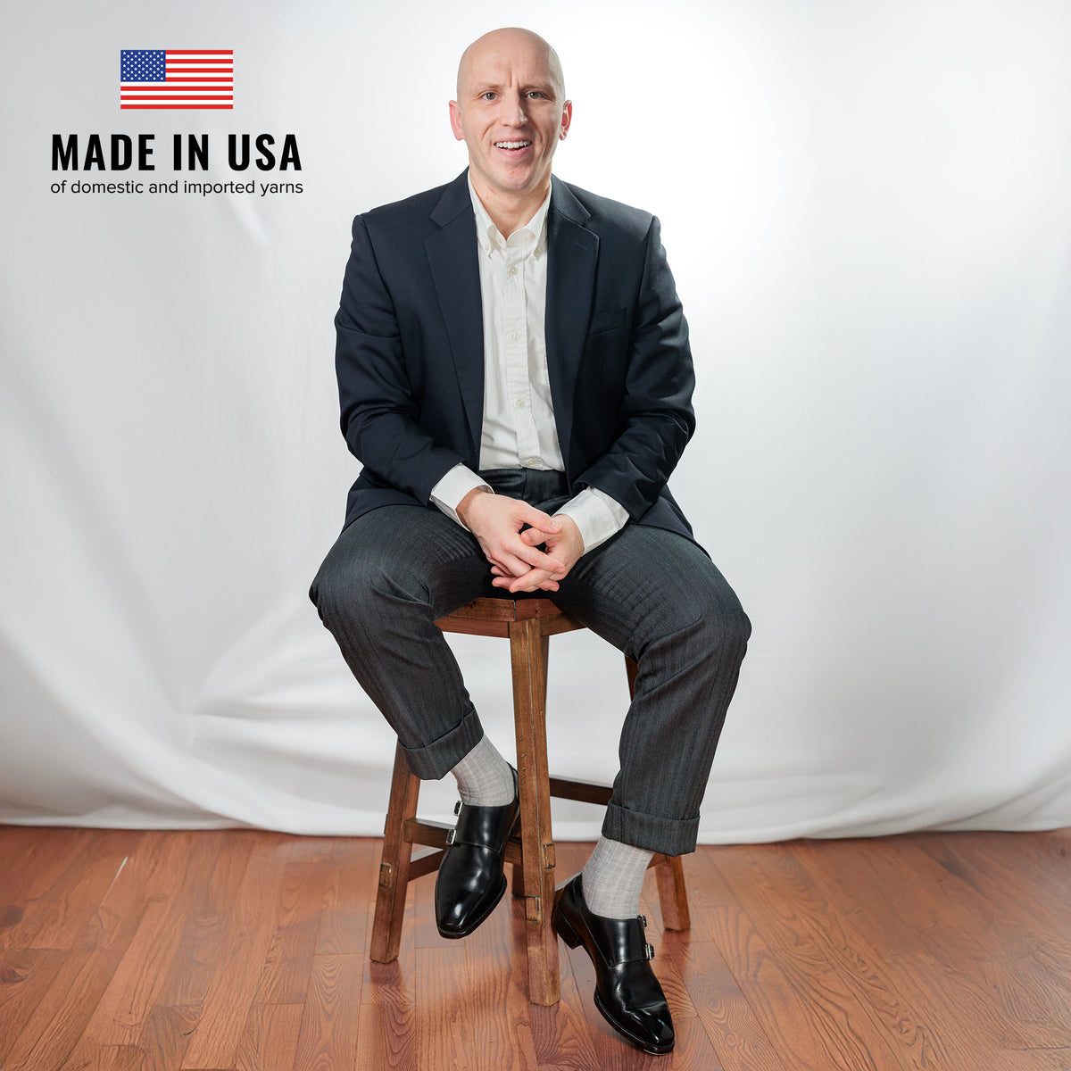 professional man seated on stool wearing light grey heather merino wool dress socks