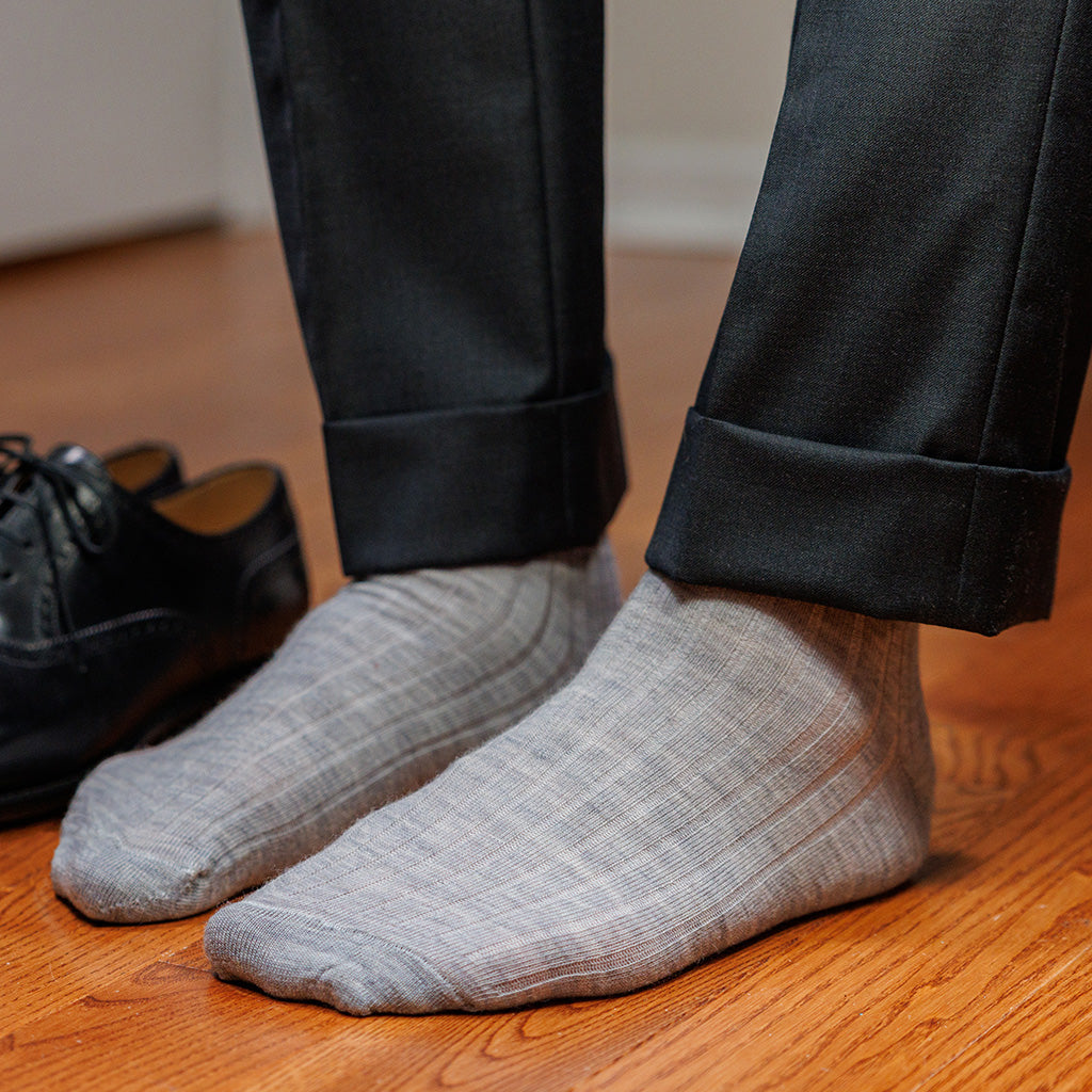 man wearing light grey heather wool dress socks standing on hardwood floor