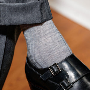 man crossing legs wearing grey suit with light grey wool dress socks and black double monkstraps