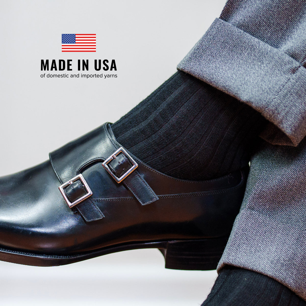 man crossing legs wearing grey slacks and black mens over the calf wool dress socks with made in usa text overlay