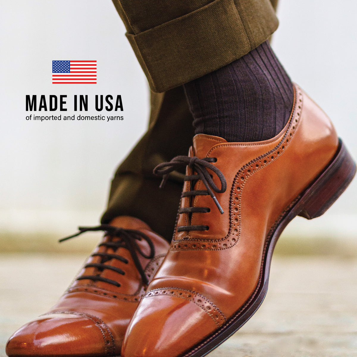 man crossing legs at the ankles standing outside wearing brown shoes, green pants, and Brown Cotton Over the Calf Dress Socks