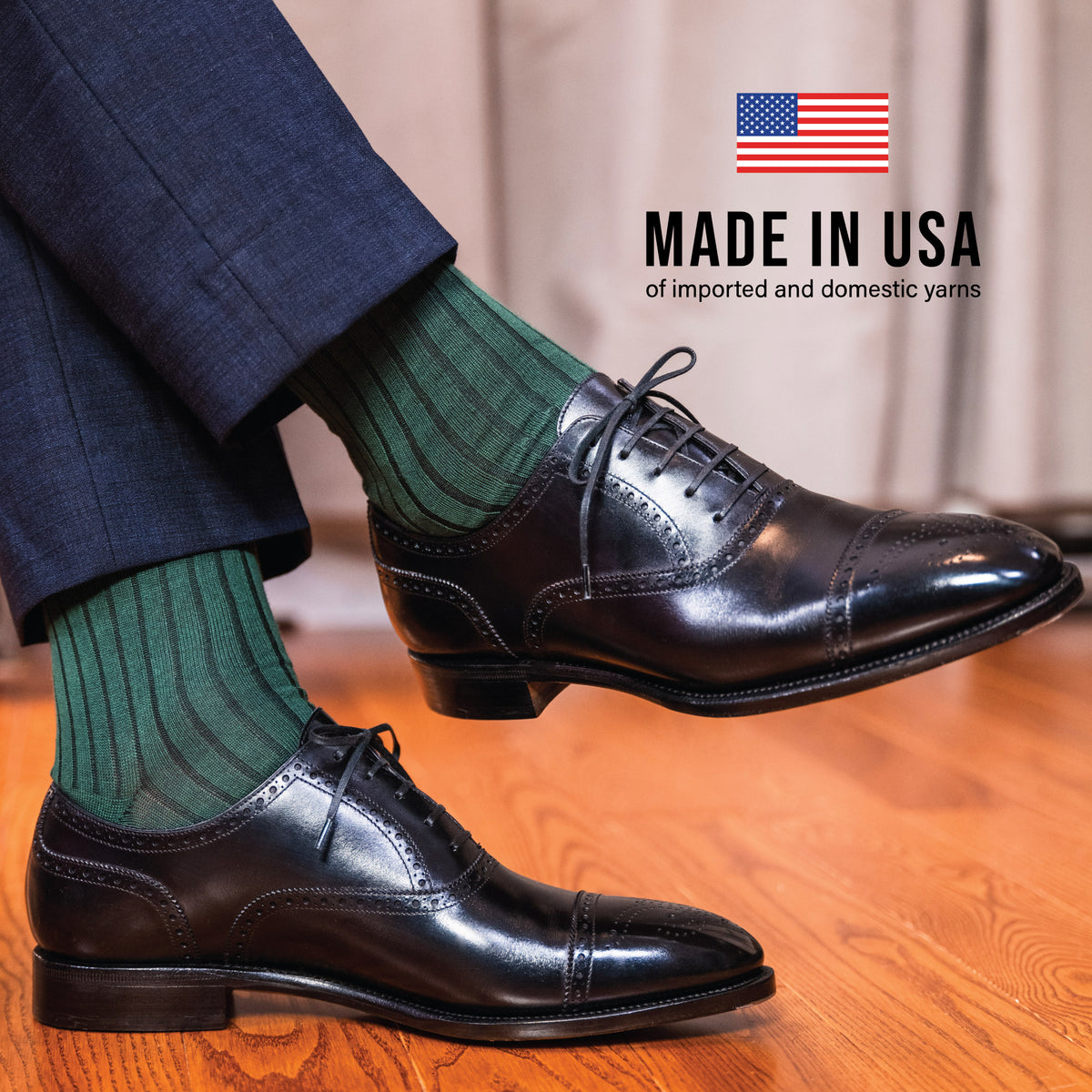 man sitting down crossing his legs wearing black shoes, nice pants andForest Green Cotton Over the Calf Dress Socks