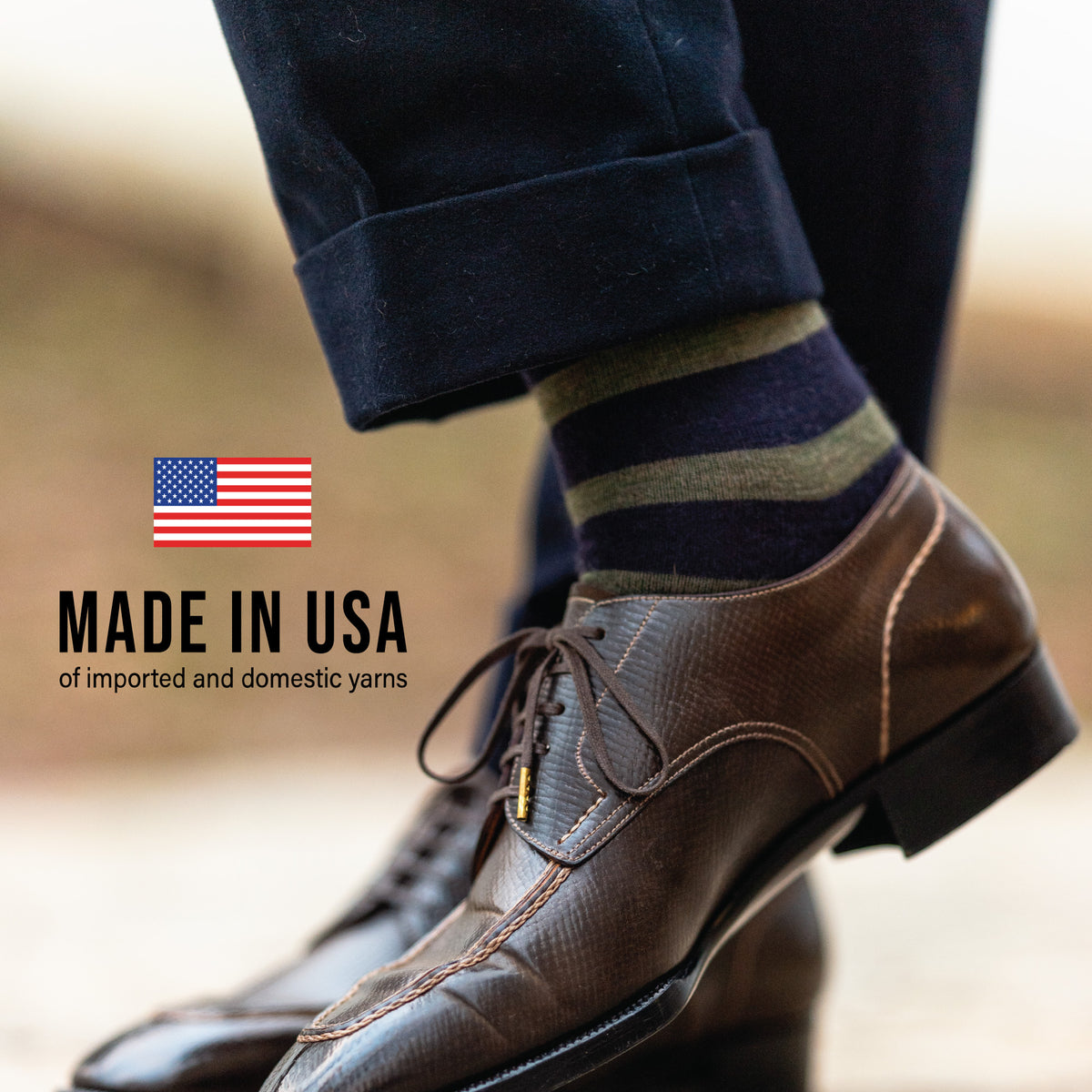 close up image of man standing outside wearing Olive Stripes on Navy Merino Wool Over the Calf Dress Socks with made in usa text overlay