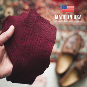 man holding a pair of burgundy merino wool over the calf ribbed mens dress socks