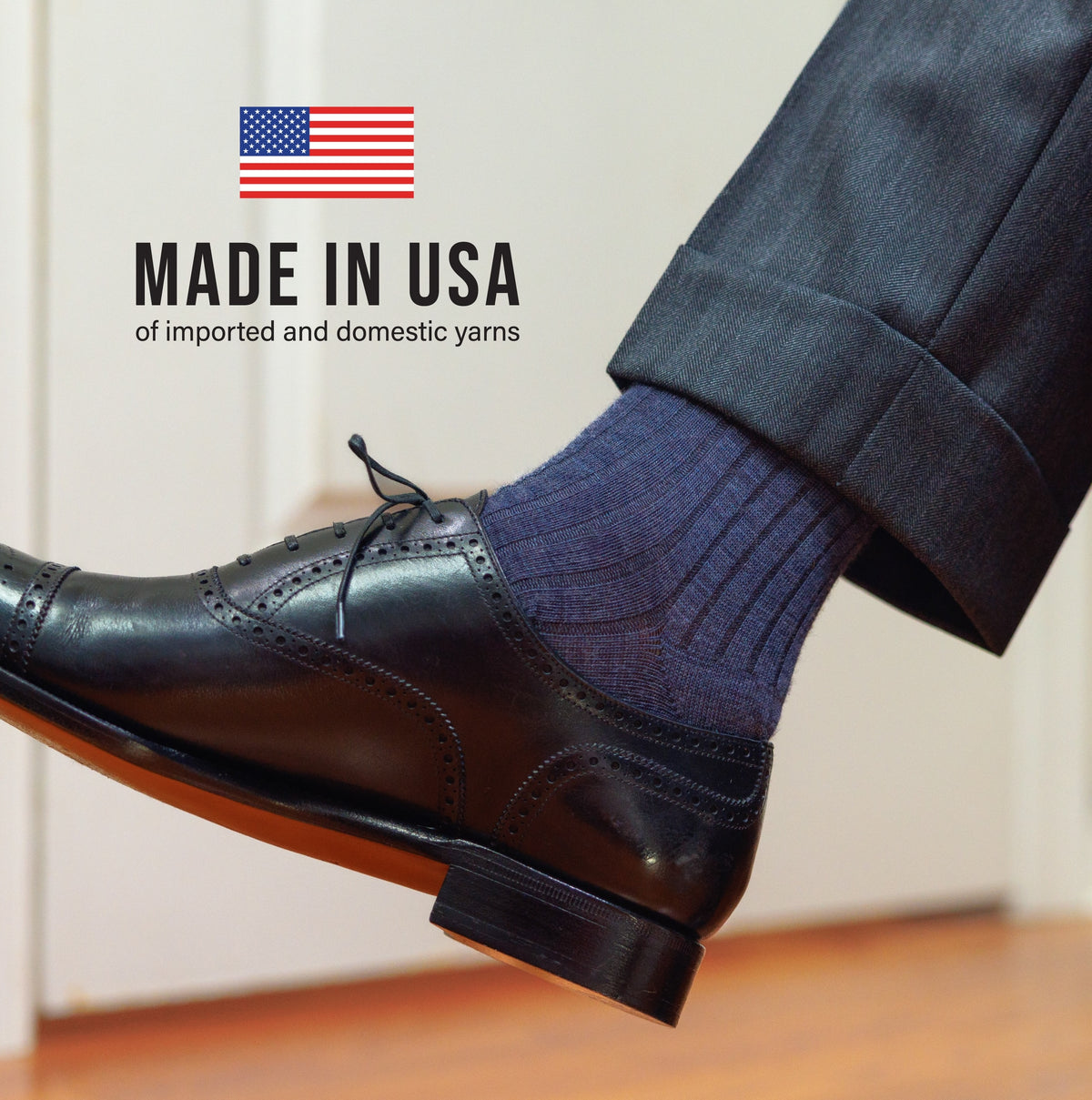 right leg of a person wearing grey slacks, black oxfords and denim ribbed merino wool dress socks with "made in usa" text overlay