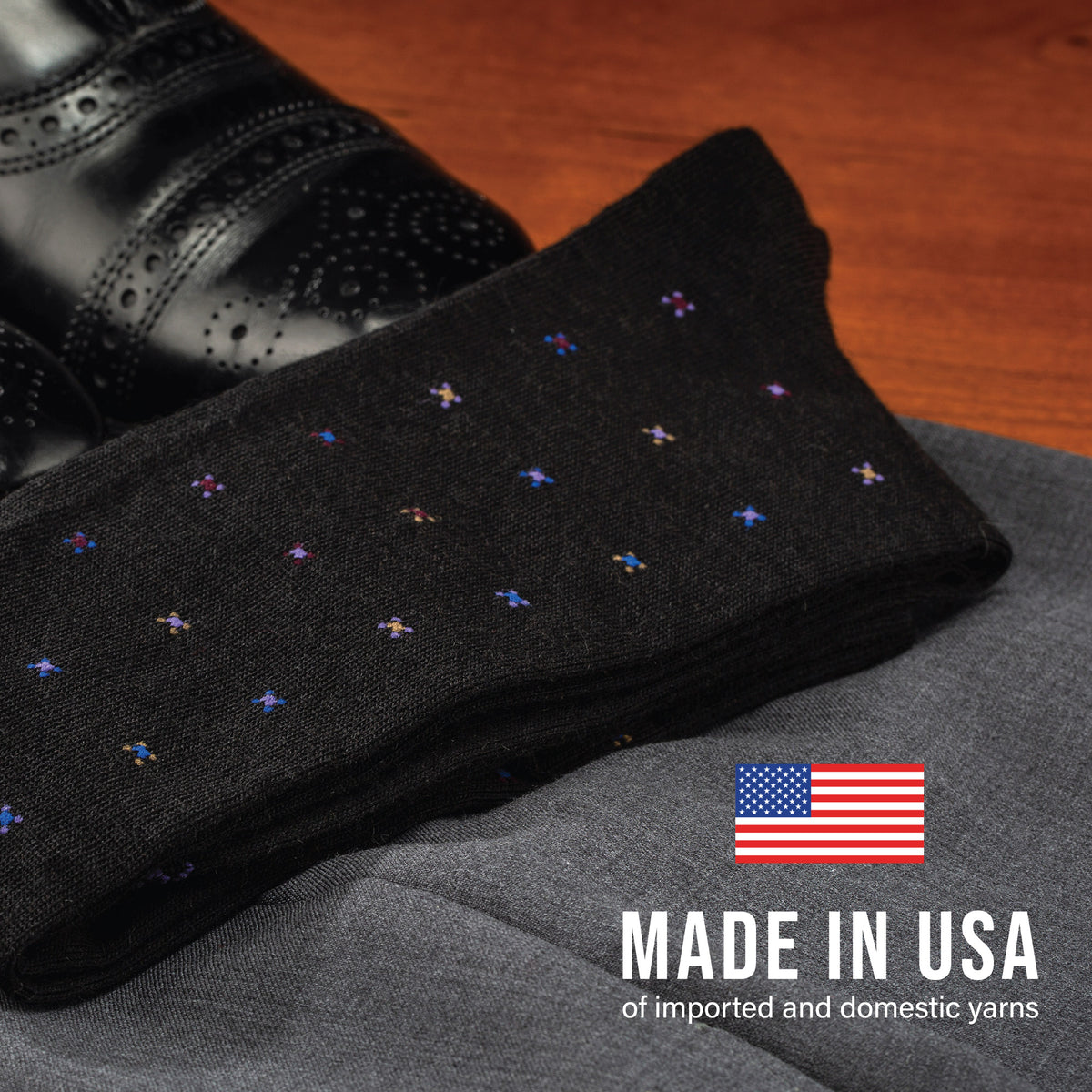 pair of Black Geometric Merino Wool Over the Calf Dress Socks laying flat on pants and dress shoes