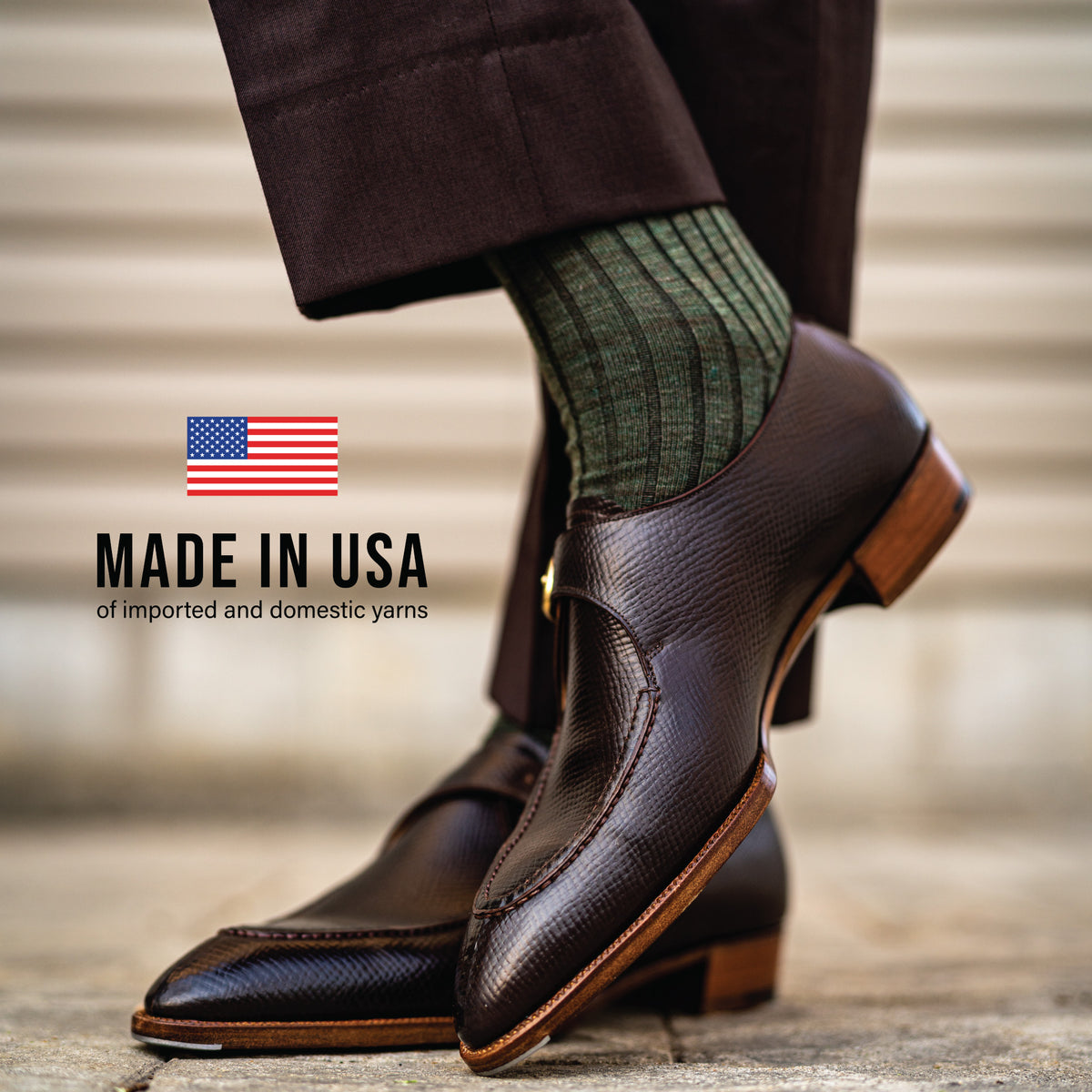 man crossing his legs wearing nice shoes and olive ribbed wool mid-calf dress socks with made in usa of imported and domestic yarns text overlay