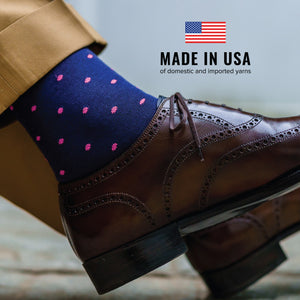 close up of person wearing nice clothes and navy mid-calf dress socks with bright pink dots with made in usa text overlay