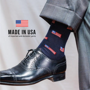 man wearing grey pants, black dress shoes and navy mid-calf merino wool socks with an american flag pattern