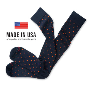 flat lay image of over the calf length merino wool socks in navy with orange dots with made in usa text overlay