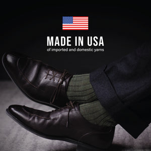 man crossing his legs wearing olive merino wool over the calf ribbed mens dress socks with made in usa text overlay