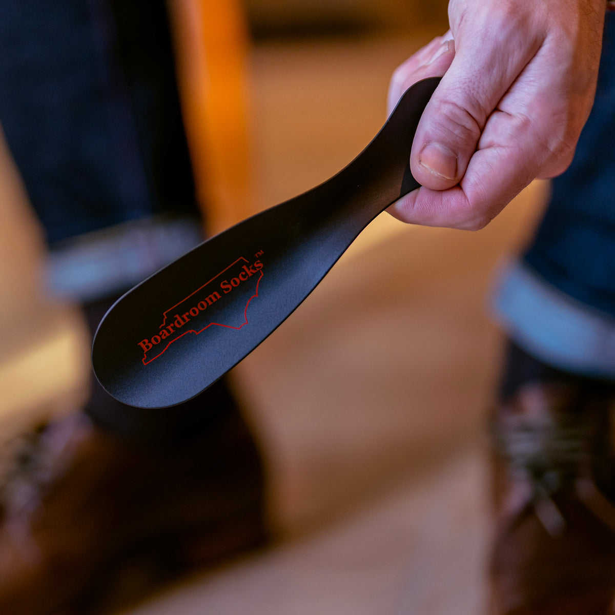man holding black metal shoe horn from Boardroom Socks