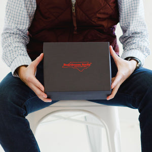 man seated holding Boardroom Socks gift box