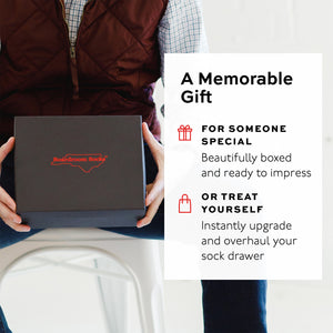 Person holding a black box with 'Boardroom Socks' branding, promotional text overlay.