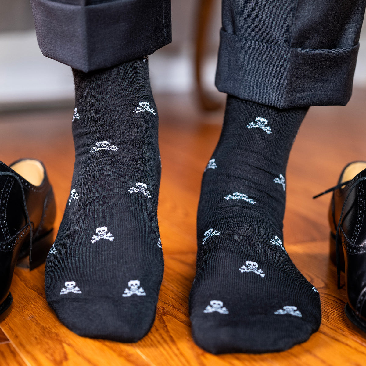 man standing on hardwood floor wearing skull dress socks
