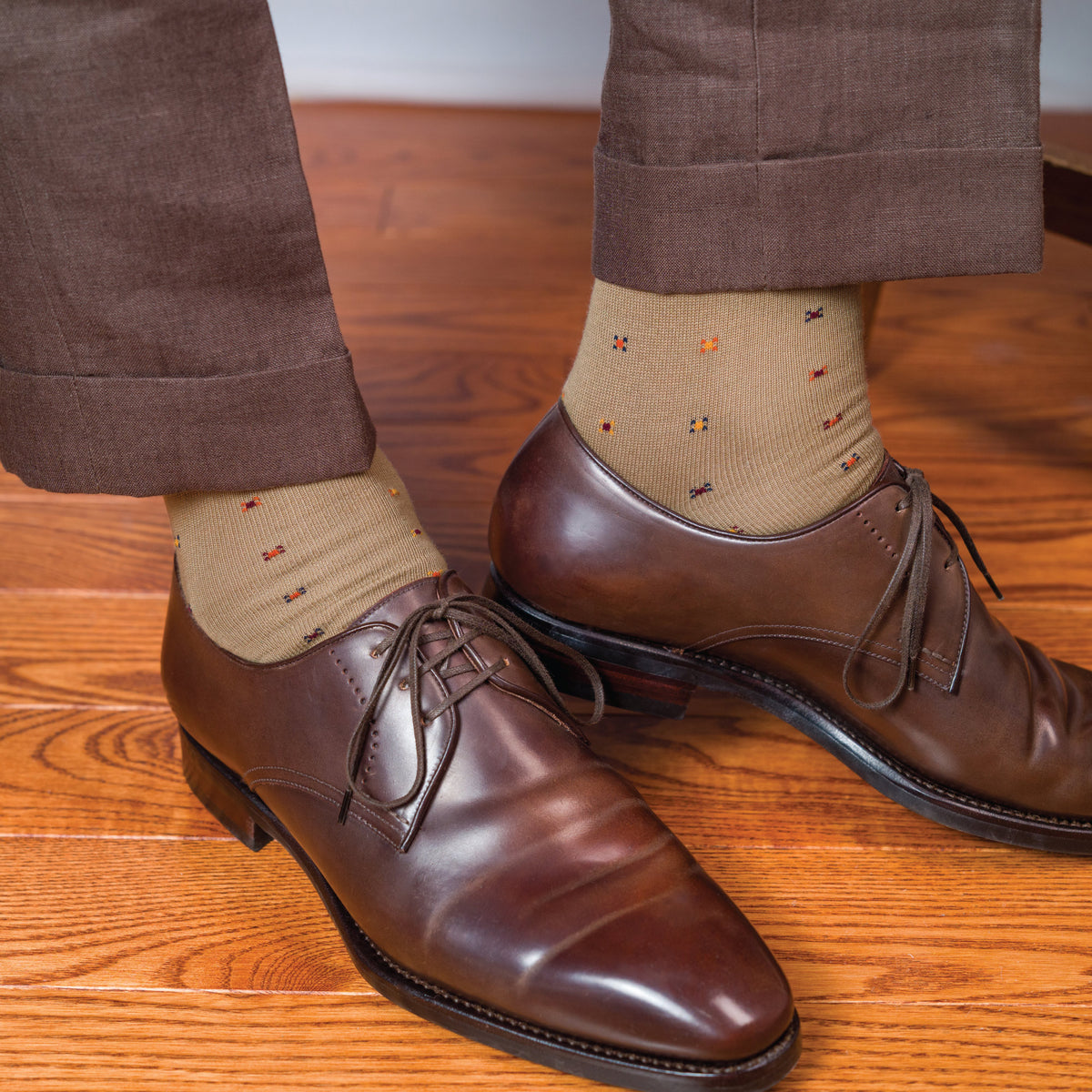 man wearing brown oxfords, brown slacks , and khaki mid calf geometric pattern socks