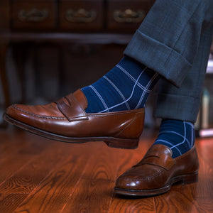 man wearing navy windowpane dress socks with a grey suit and brown penny loafers