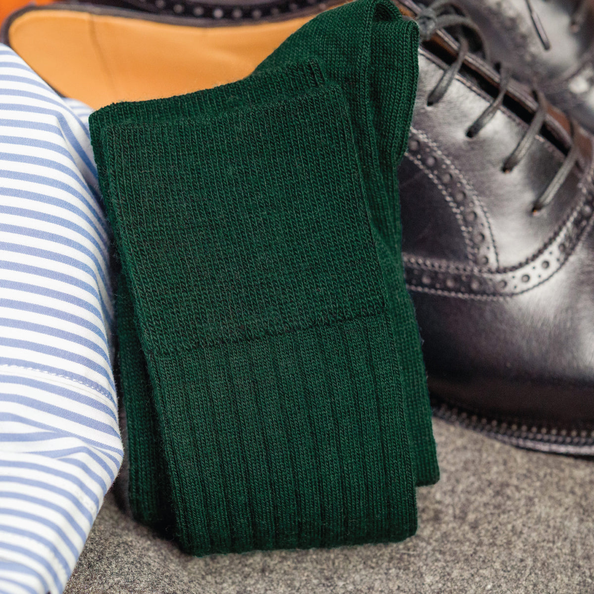 pair of Forest Green Merino Wool mid-Calf Dress Socks laying on top of nice clothing and a pair of black shoes