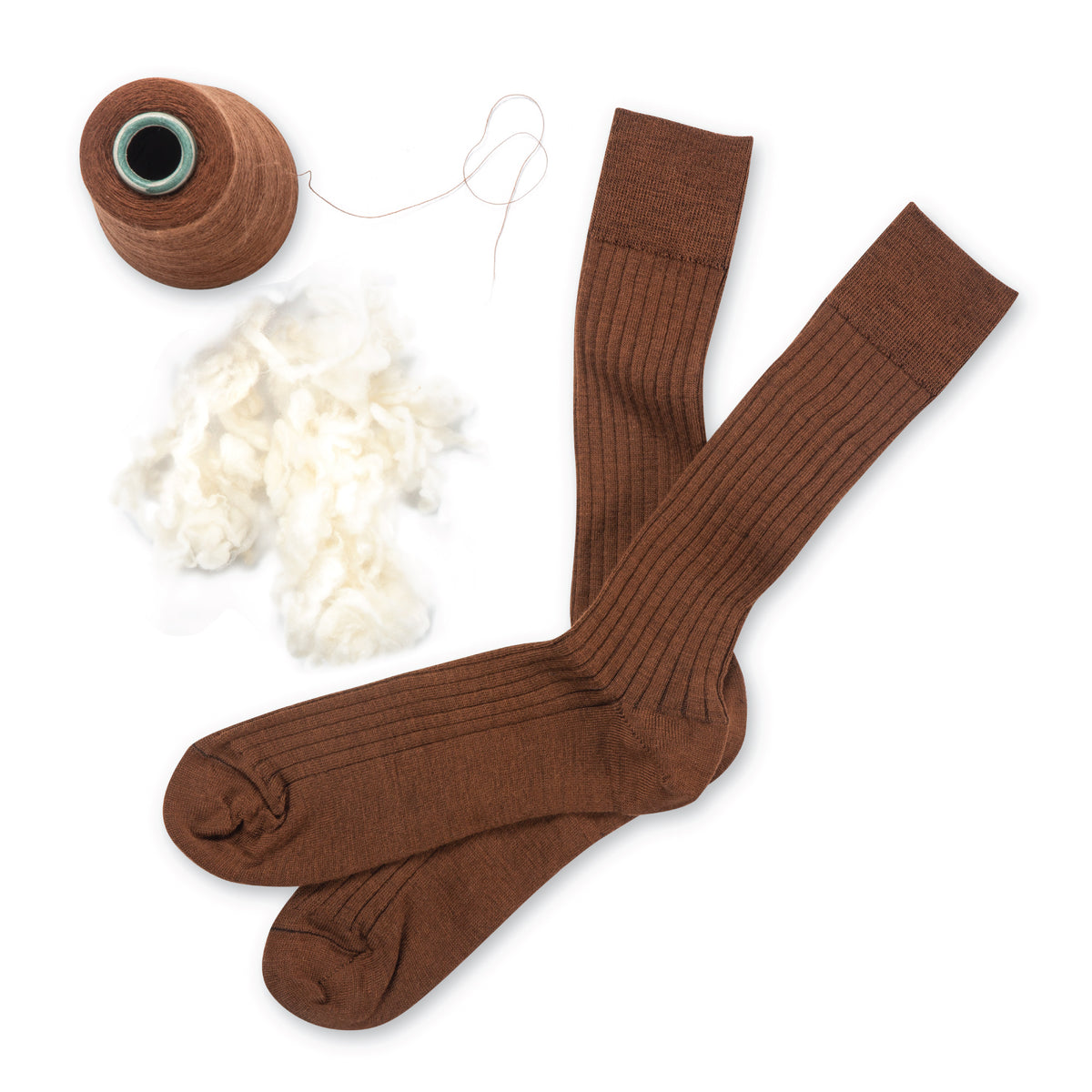a pair of brown mid-calf merino wool dress socks laying on a white background with yarn and wool beside them