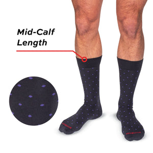 model wearing mid-calf length grey cotton dress socks with purple polka dots standing with a white background