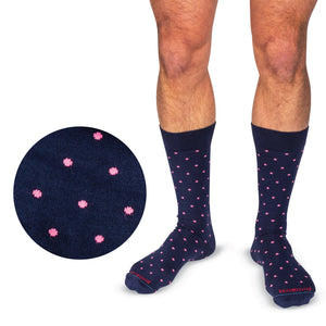 model wearing navy mid-calf dress socks with bright pink dots on a white background
