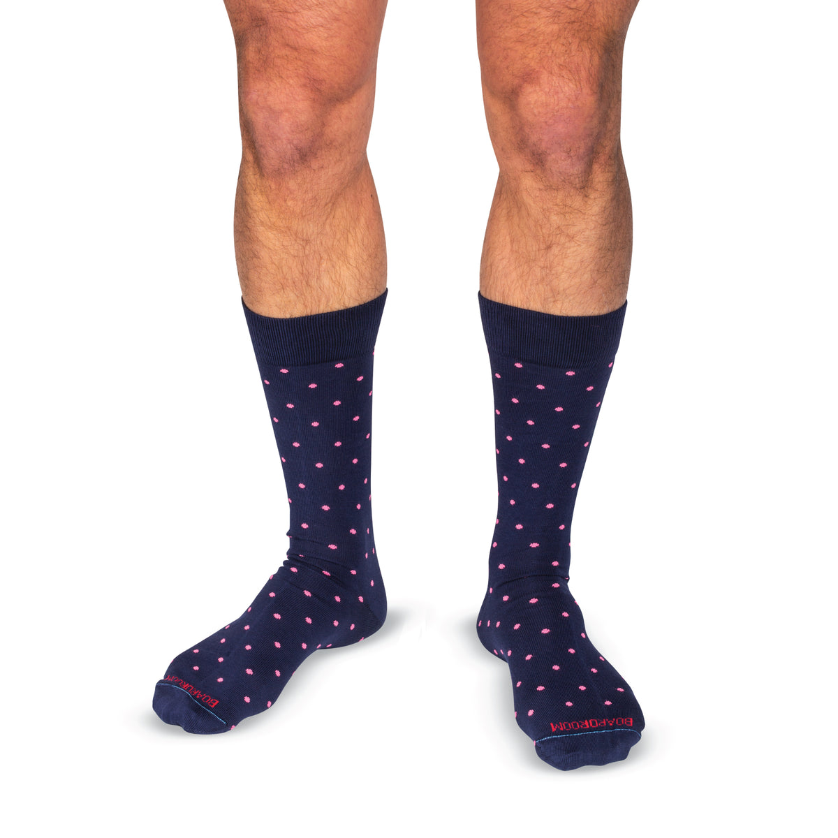 model wearing navy mid-calf dress socks with bright pink dots on a white background