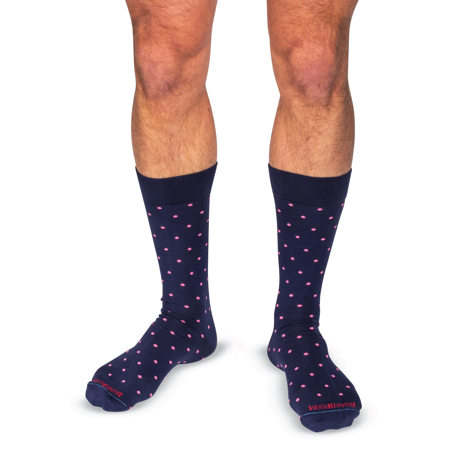 model wearing navy mid-calf dress socks with bright pink dots on a white background