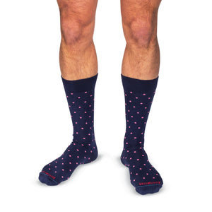 model wearing navy mid-calf dress socks with bright pink dots on a white background
