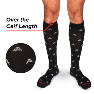 white background with model wearing over the calf merino wool black socks with skull and bone pattern