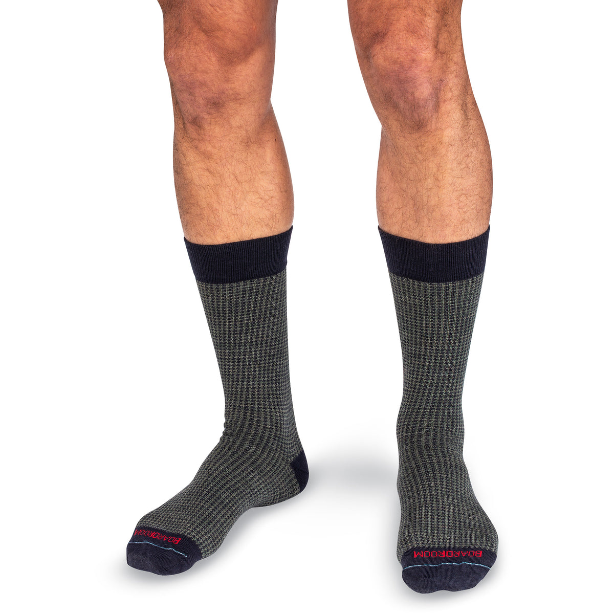 model wearing pair of mid-calf length merino wool dress socks in olive and navy houndstooth pattern