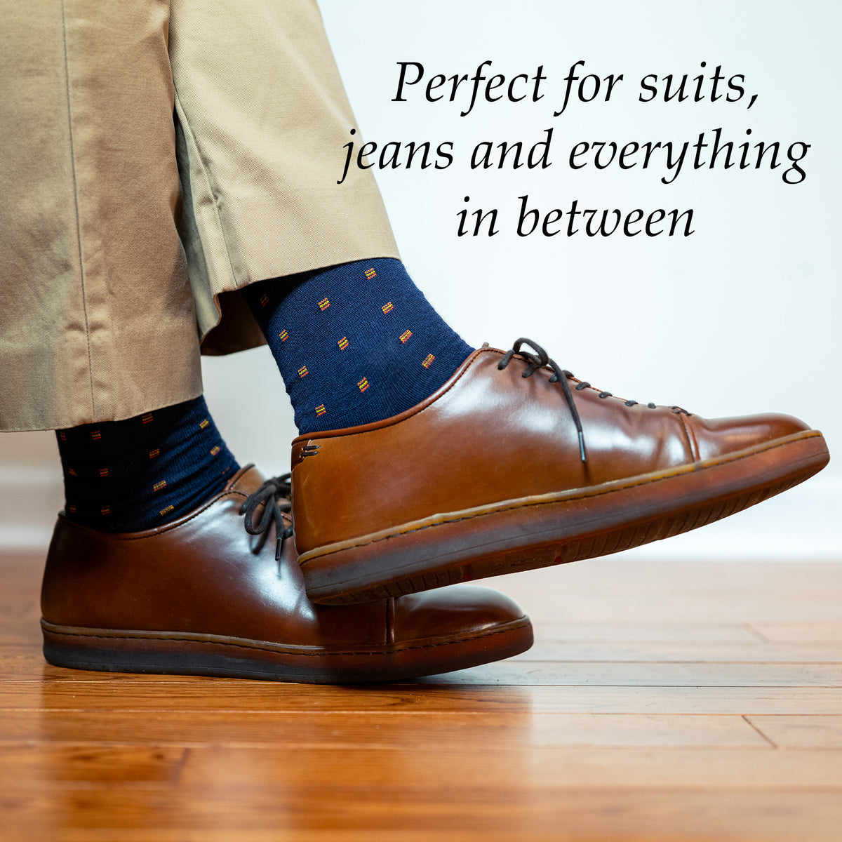 man crossing ankles wearing orange and navy dress socks with dress sneakers