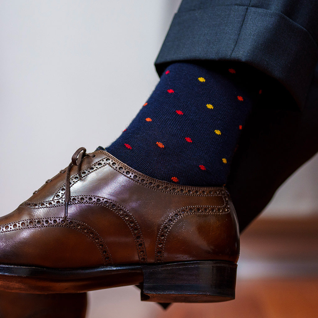 navy dress socks decorated with colorful polka dots worn with brown wingtips and a grey suit