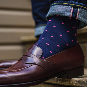close up of a person wearing jeans and navy mid-calf dress socks with bright pink dots