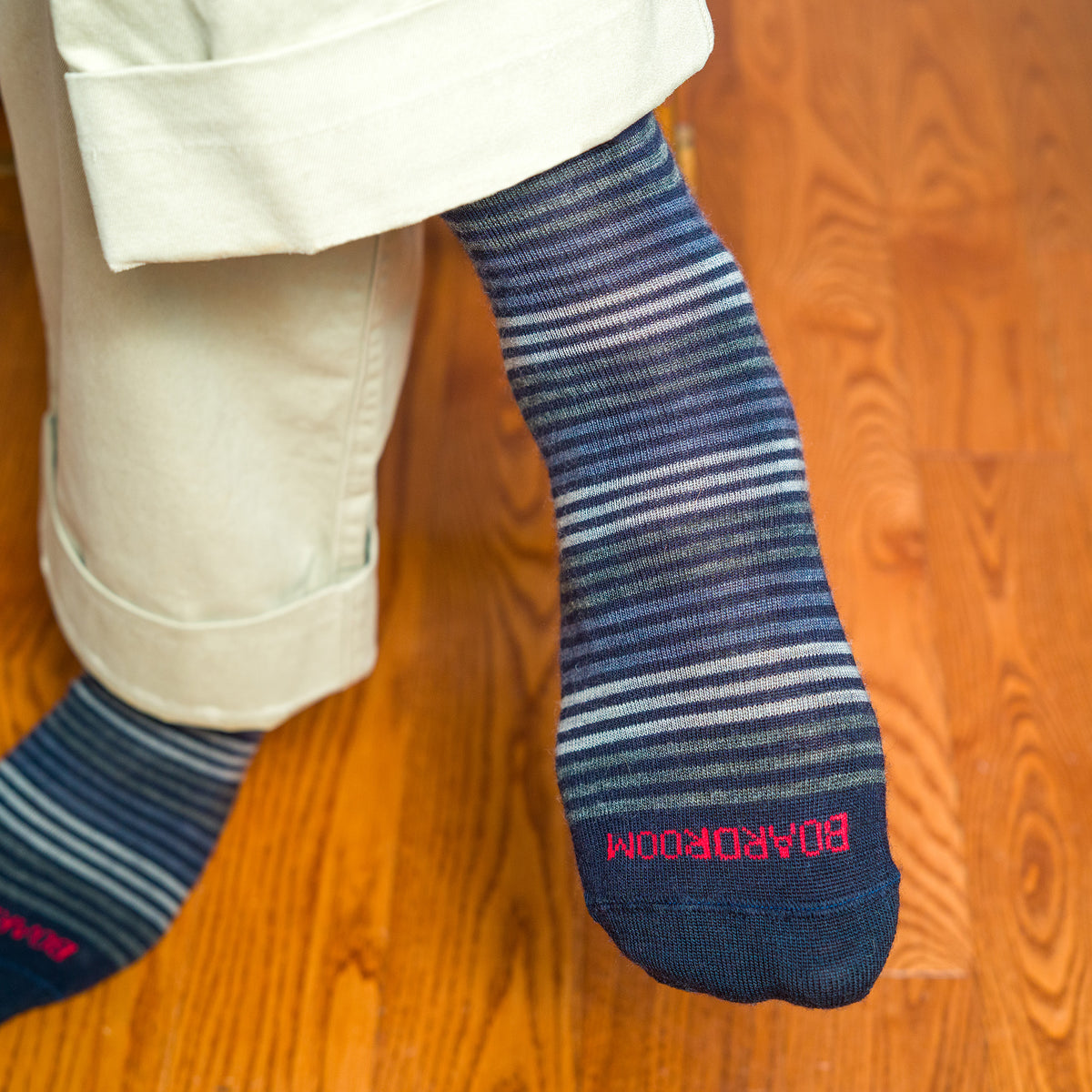 person wearing blue striped dress socks with 'BOARDROOM' branding paired with khakis