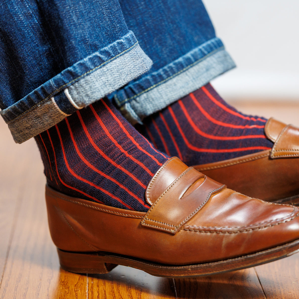 man wearing jeans with navy wool over the calf dress socks adorned with red shadow vertical stripes