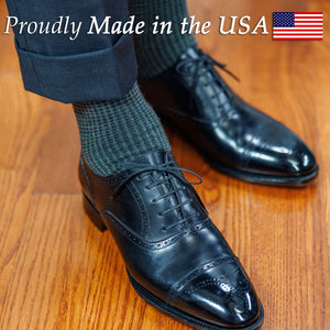 man wearing charcoal suit with classic green and blue houndstooth dress socks and black oxfords