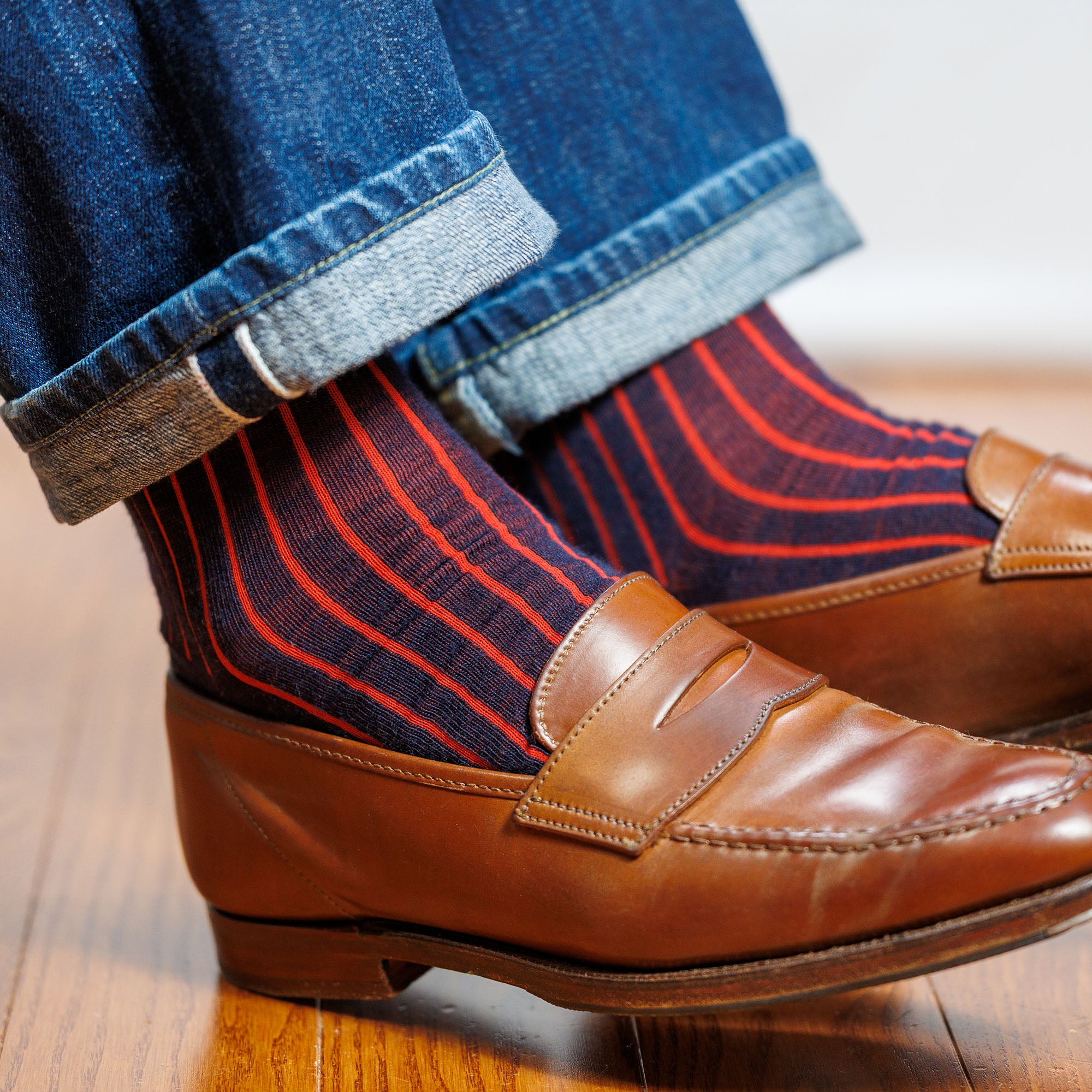 navy and red vertical striped wool dress socks worn with jeans and brown penny loafers