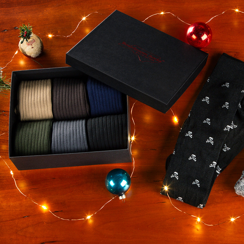 opened gift box filled with dress socks and a pair of Jolly Roger socks surrounded by holiday decor