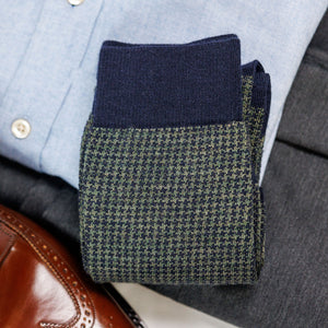 pair of olive and navy houndstooth dress socks atop a business casual outfit