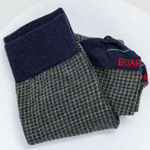 pair of olive and navy houndstooth merino wool dress socks folded on white table