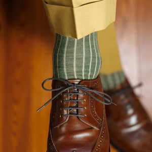 man crossing legs wearing olive green shadow stripe dress socks with tan slacks and brown wingtips