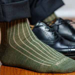 man wearing olive and tan vertical striped wool dress socks standing on hardwood floor