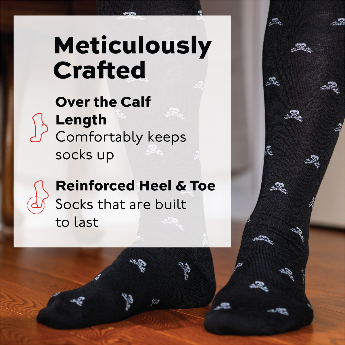 man standing on a wood floor wearing over the calf length merino wool dress socks in a skull and bone repeating pattern