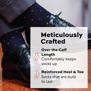 mans legs crossed at the ankle wearing black oxfords and over the calf merino wool navy socks with a tri-color dot pattern